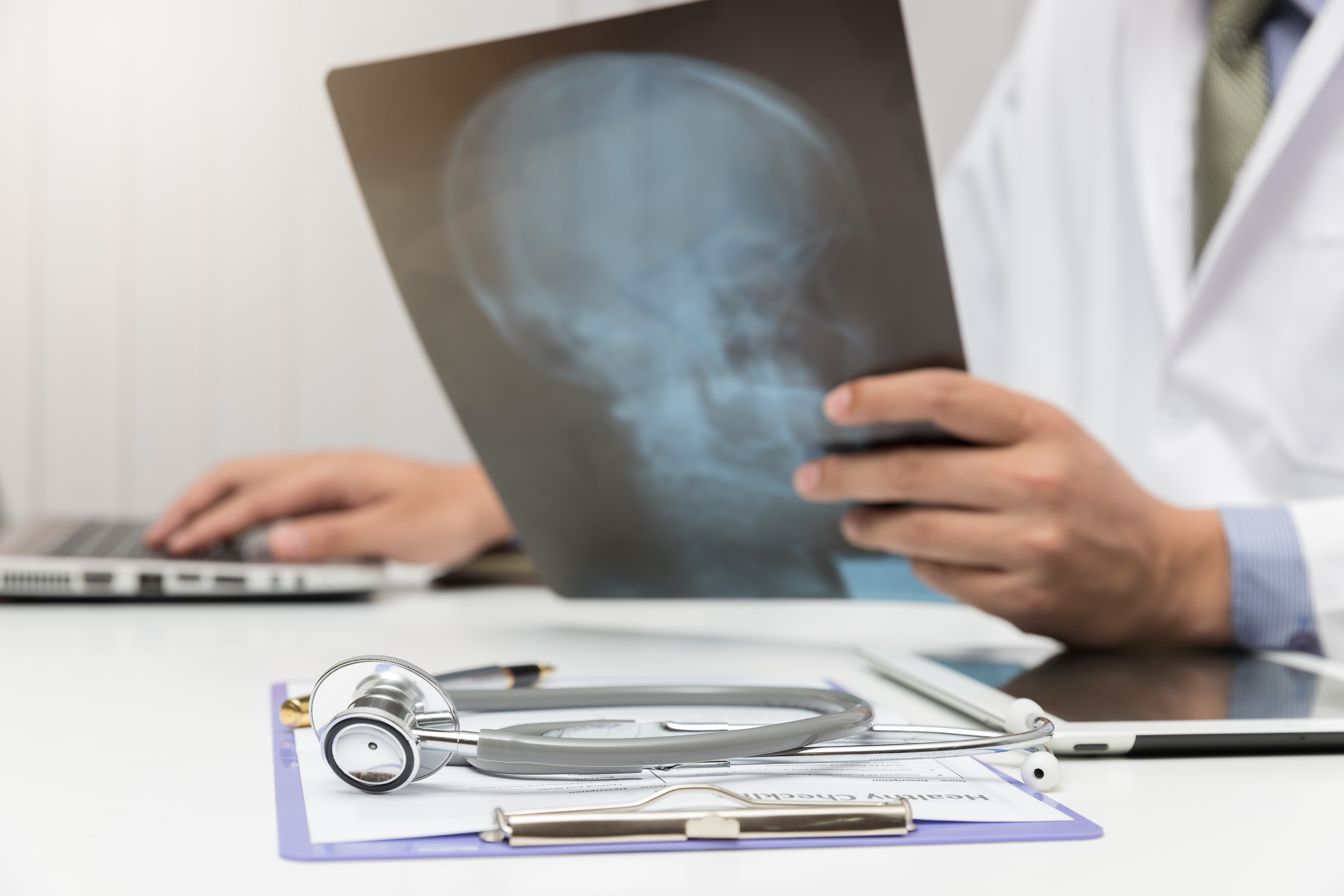 Doctor looking head x-ray film in office.